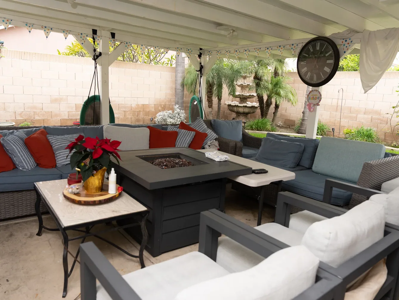 Covered patio with gray sectional sofas around a modern fire pit table.